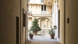 A corridor with arched ceilings, potted plants, and a tiled floor. - Navona Grand Suite (Rome)