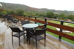 A terrace with a wooden railing, a round table, and black wicker chairs. - Babaneuris Marani (Akhmeta)
