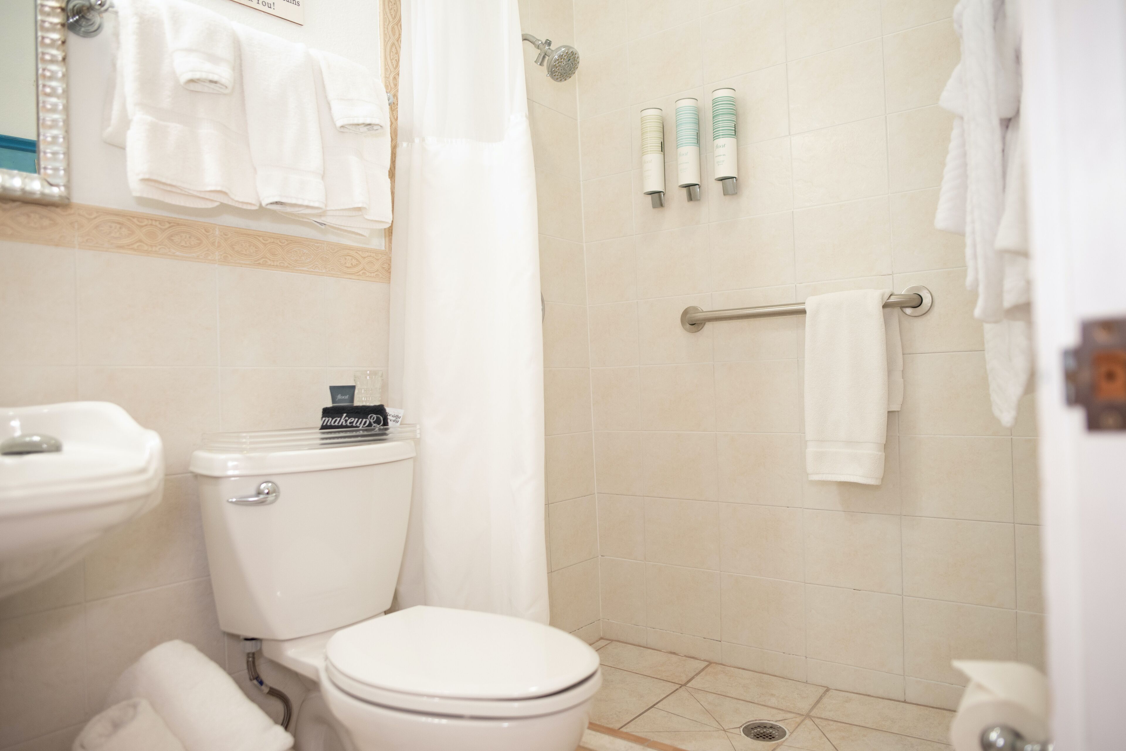 A bathroom with a toilet, sink, shower, and towel rack.