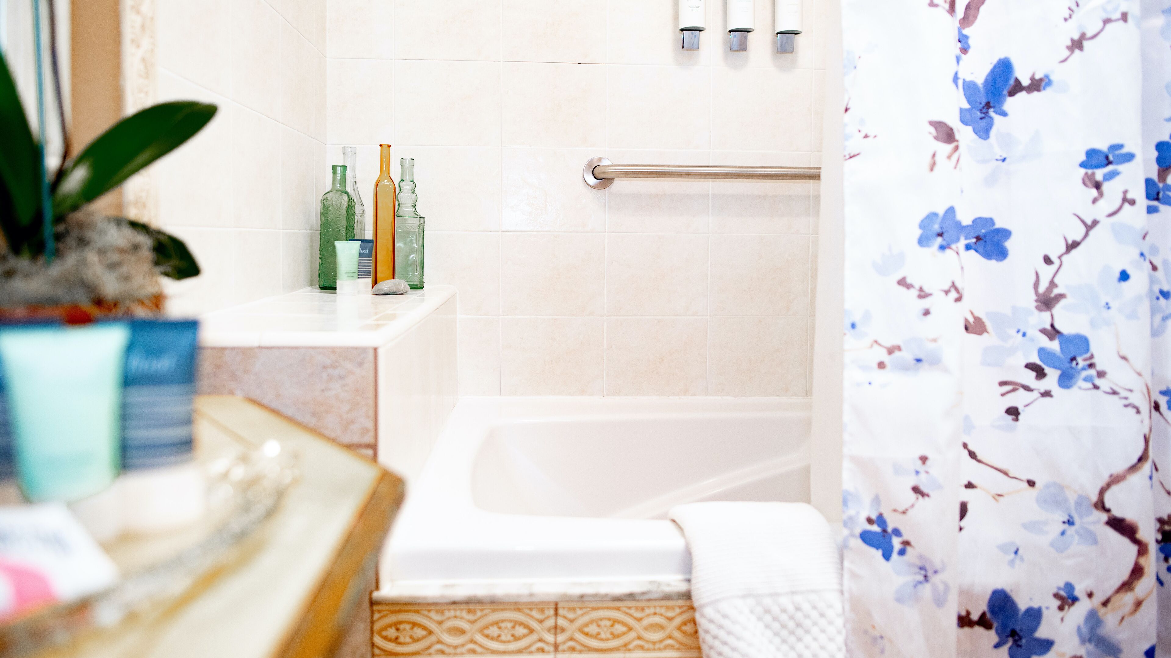 Un baño con bañera, zona de ducha y lavabo con artículos de aseo.