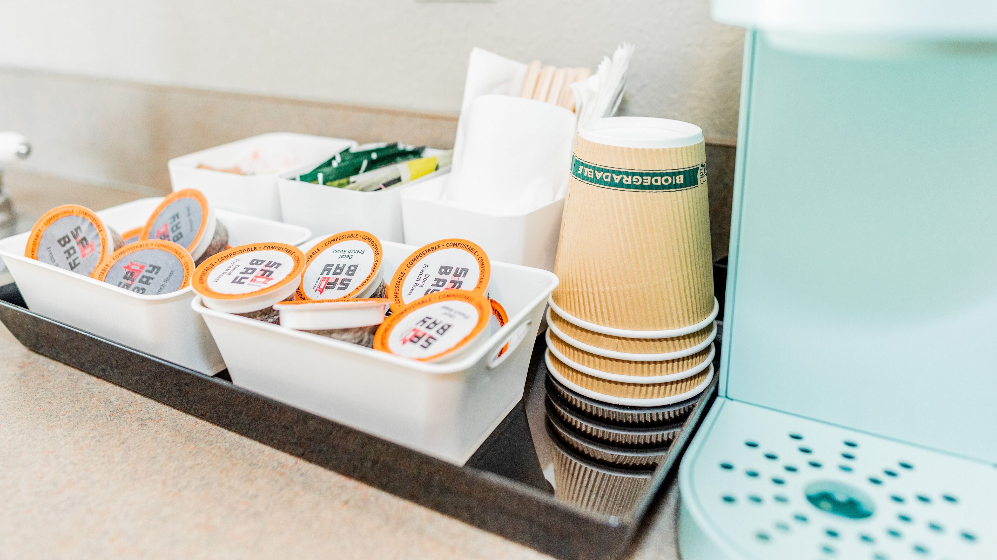 A tray with disposable cups and containers labeled "BIDDER'S BAY" and "BIODEGRADABLE."