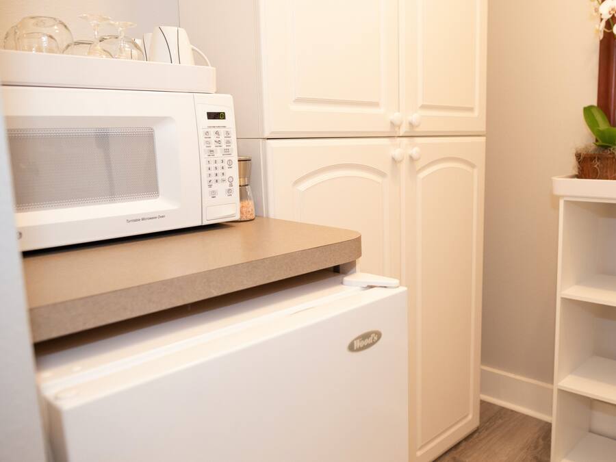 A kitchen with a microwave, a small refrigerator, and a white cabinet.