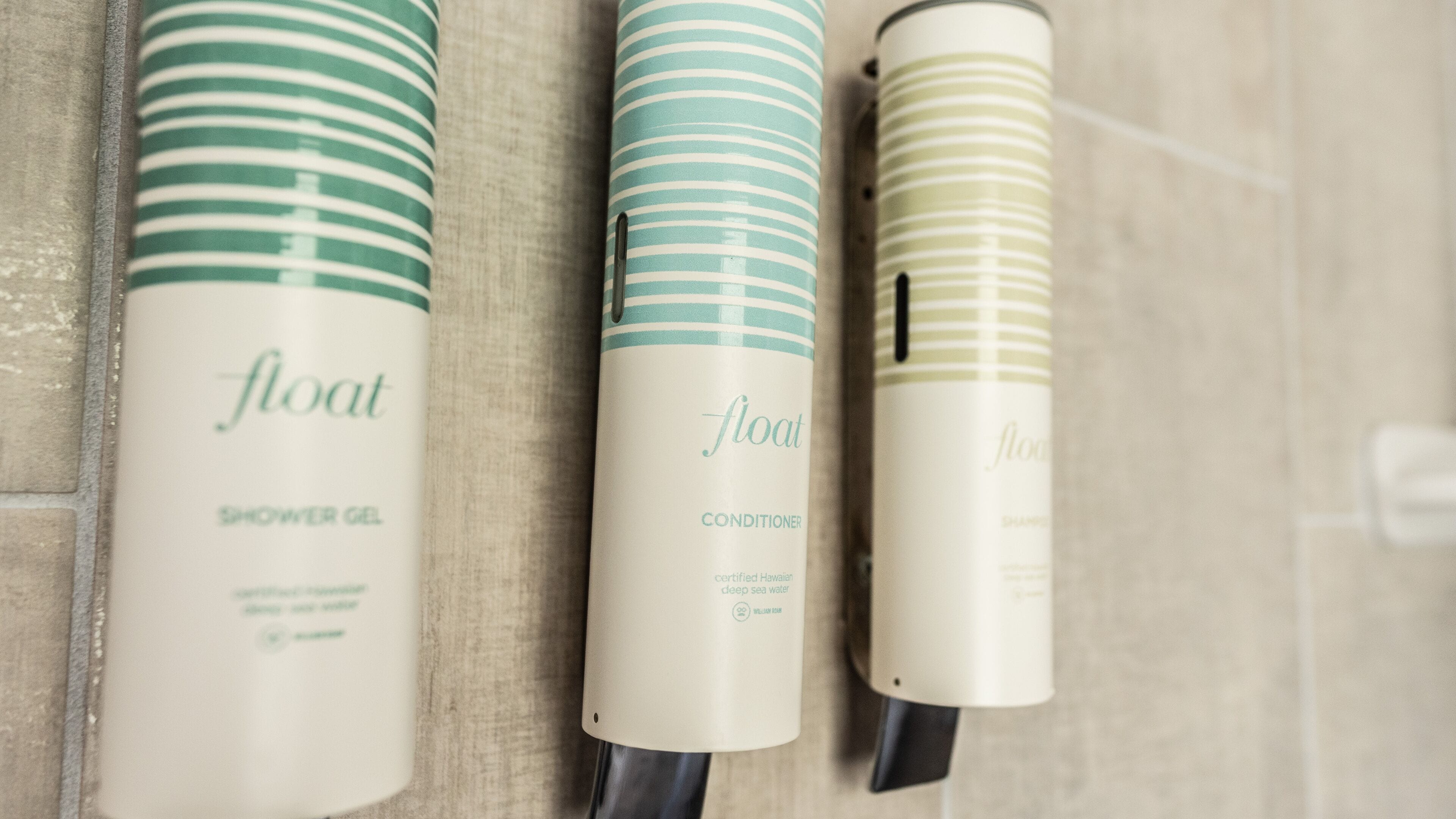 Tres botellas de productos 'float' sobre una superficie de baldosas.
