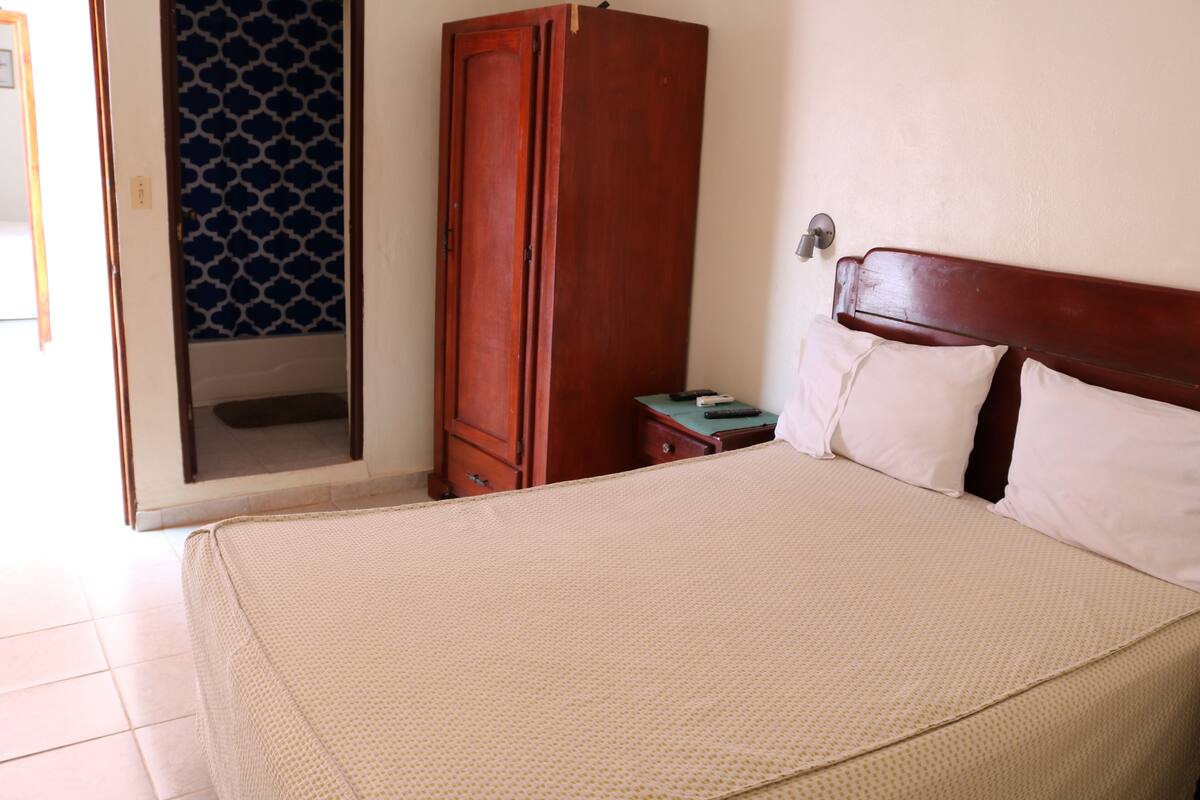 Ein Schlafzimmer mit einem Bett, einem Holzschrank und einem kleinen Nachttisch.