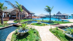 Ein Resort mit mehreren Pools, Sitzgelegenheiten im Freien und üppiger Bepflanzung.
