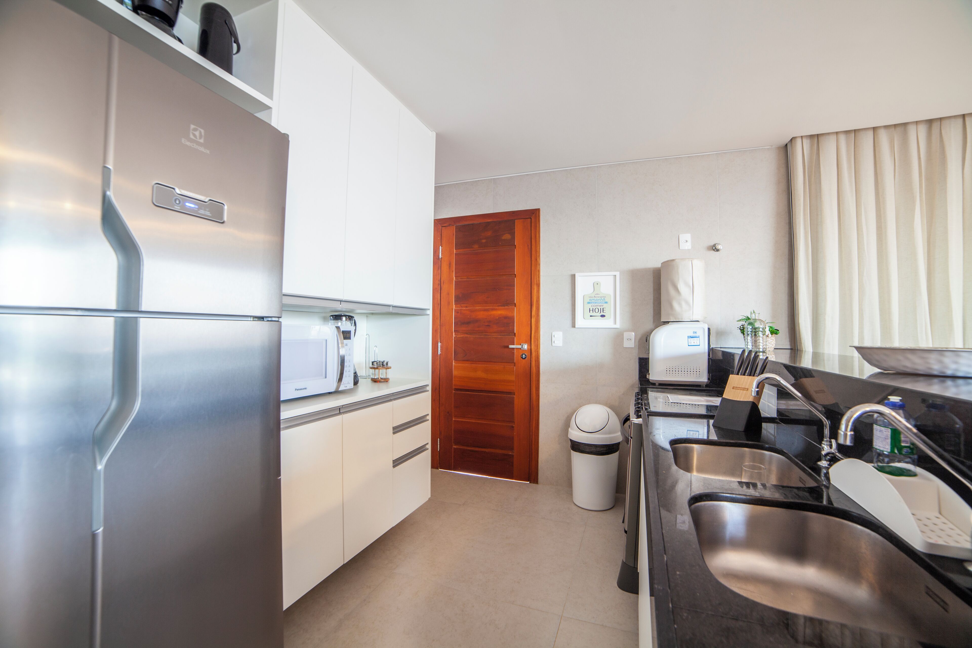 A compact kitchen with stainless steel appliances, a wooden door, and a modern sink area.