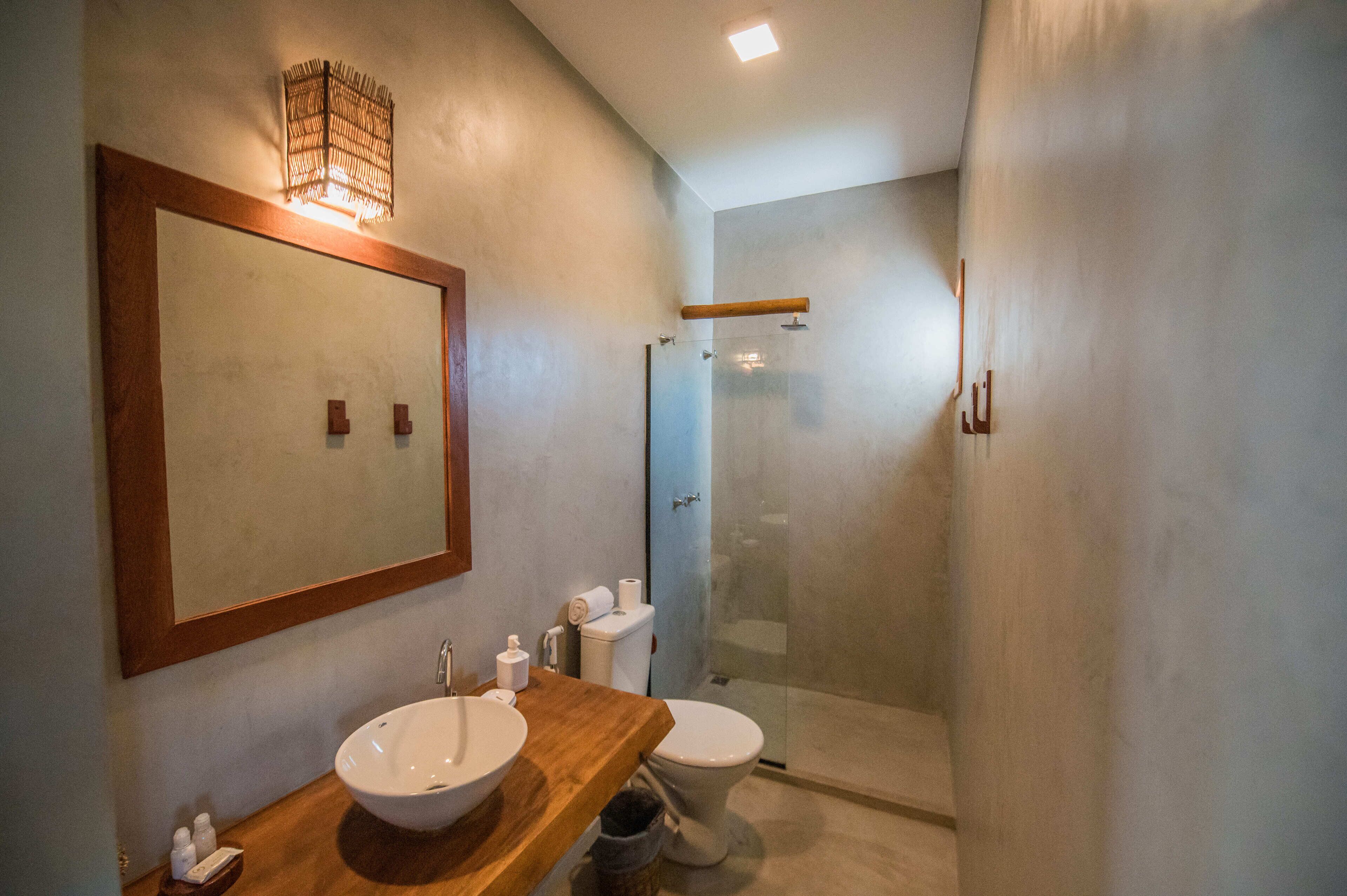A bathroom with a wooden vanity, a large mirror, a glass shower enclosure, and a toilet.