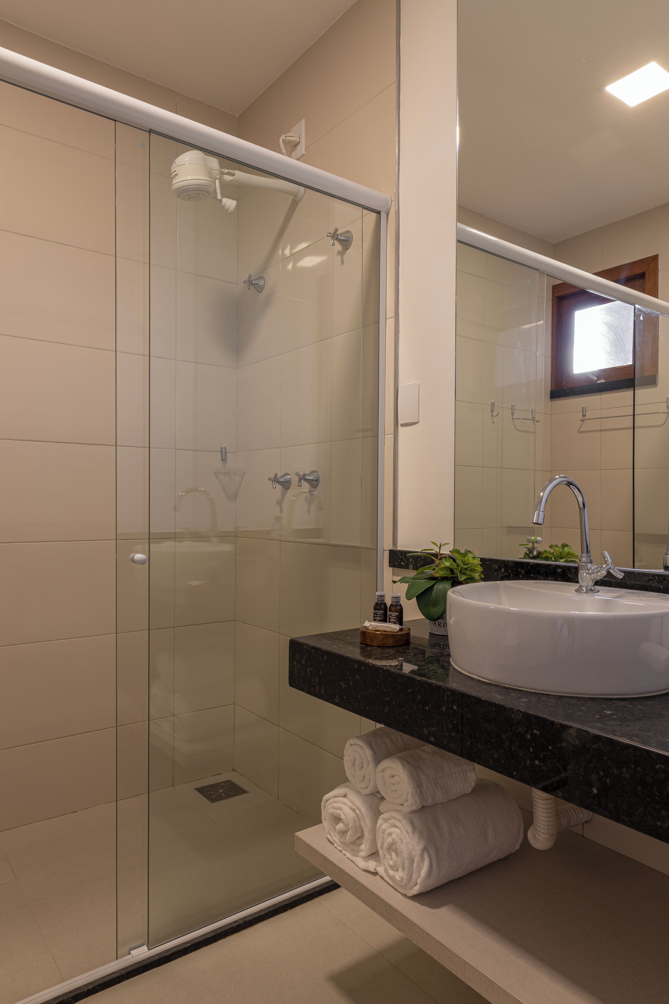 A modern bathroom with a glass-enclosed shower, a white sink, and a black countertop.