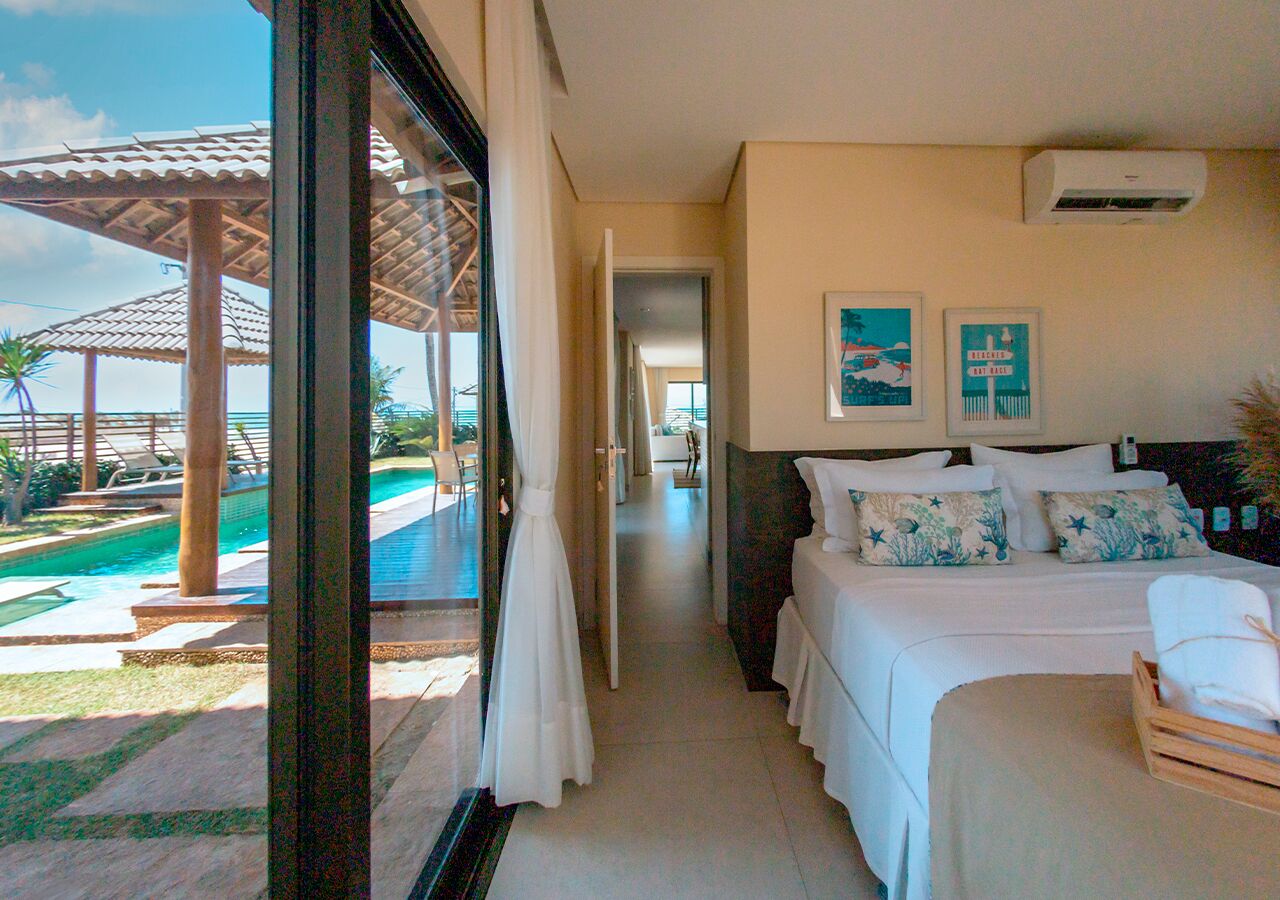 A hotel room with a bed, a small table, a window with a view of a pool and outdoor area.