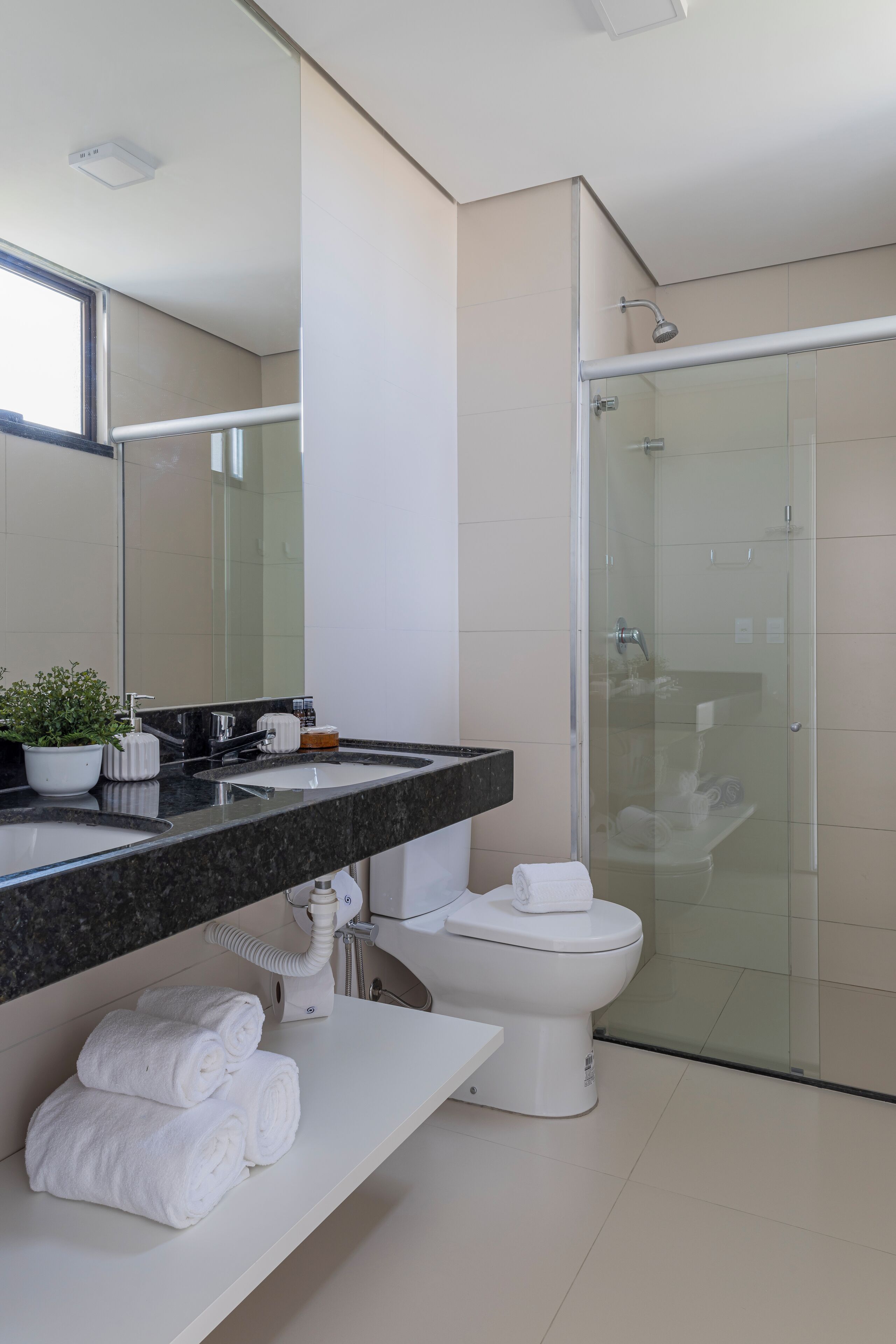 Un baño moderno con cabina de ducha acristalada, inodoro blanco y lavamanos de mármol.