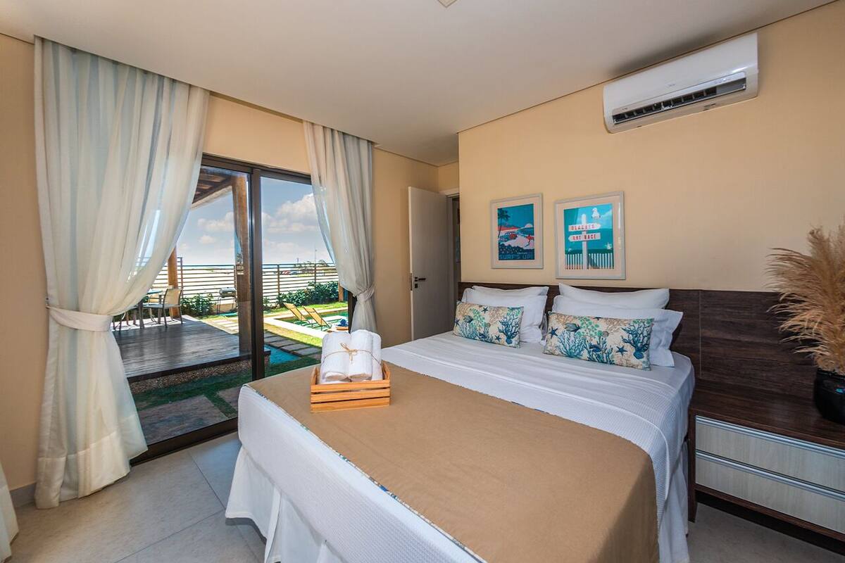 Habitación de hotel con cama, mesita de noche, ventana con cortinas y vista al exterior.