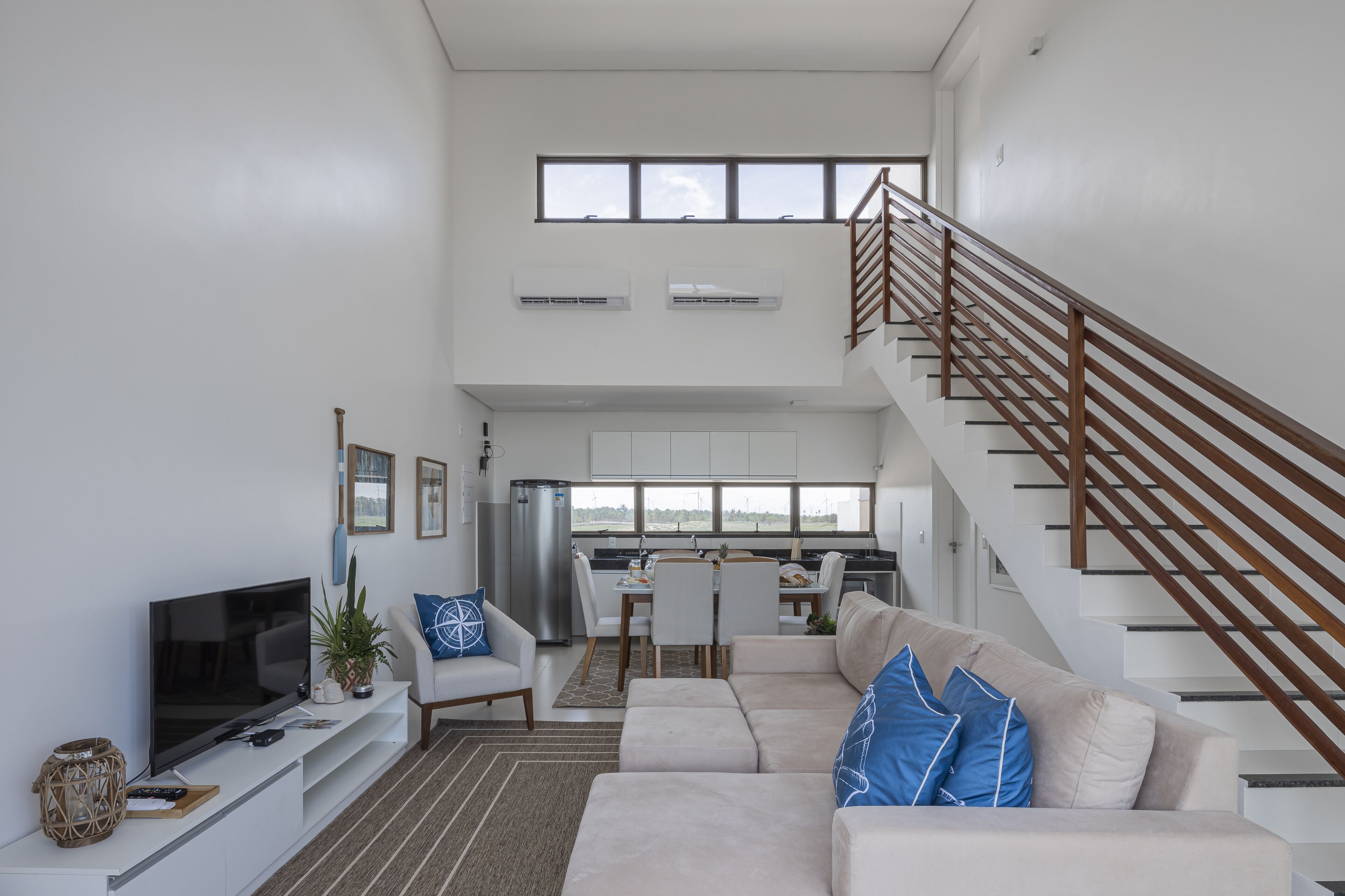 A modern living room with a flat-screen TV, sofa, and dining area.