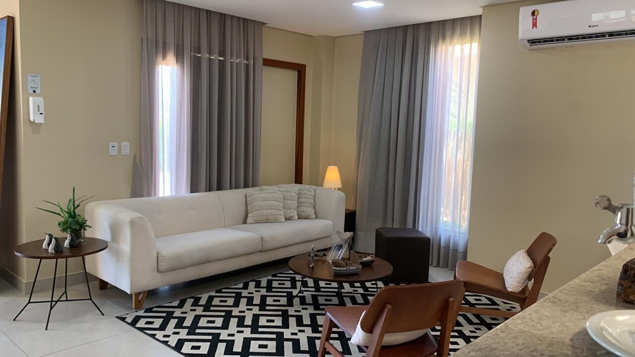 A modern living room with a sofa, coffee table, and chairs, a small side table with a plant, and a lamp.