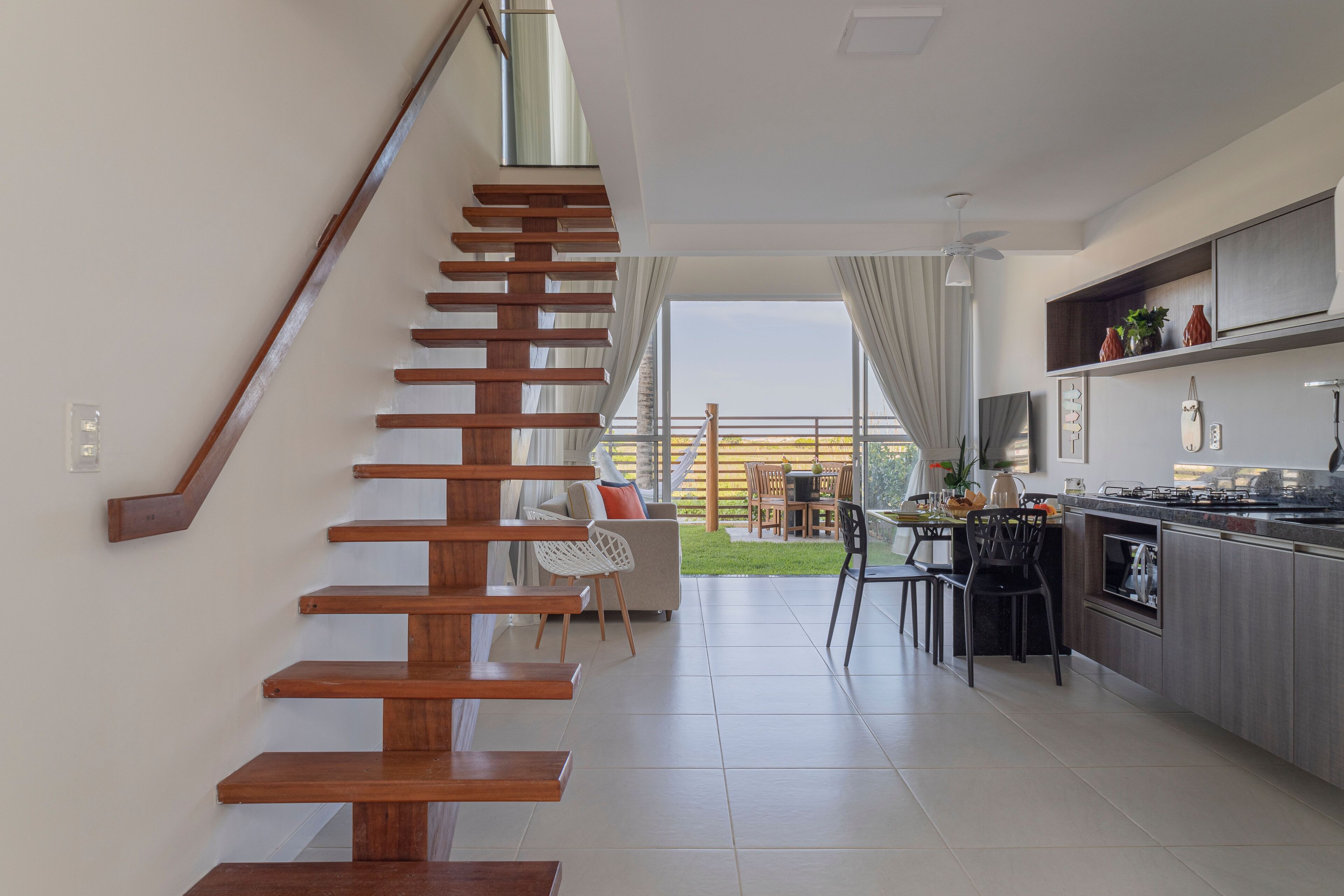 A modern kitchen with a wooden staircase leading to a balcony.