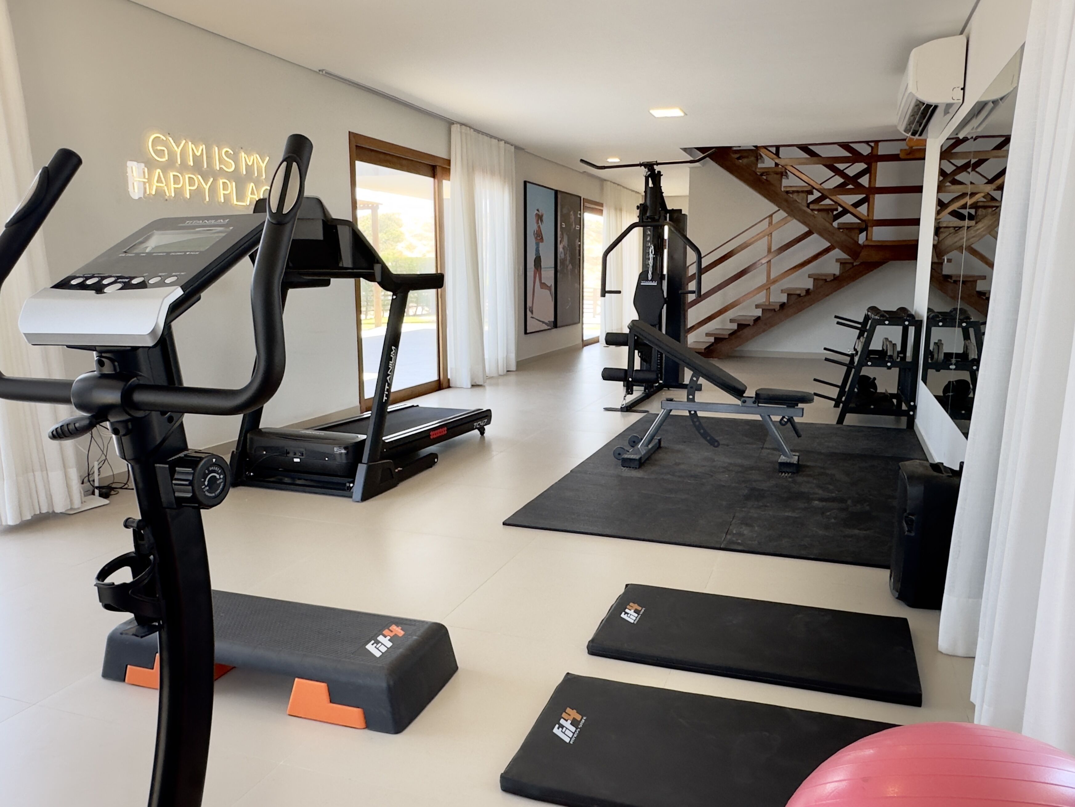 A home gym with treadmills, weight machines, and exercise mats.