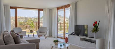 Una sala moderna con un sofá, sillones, una mesa de centro y un televisor.