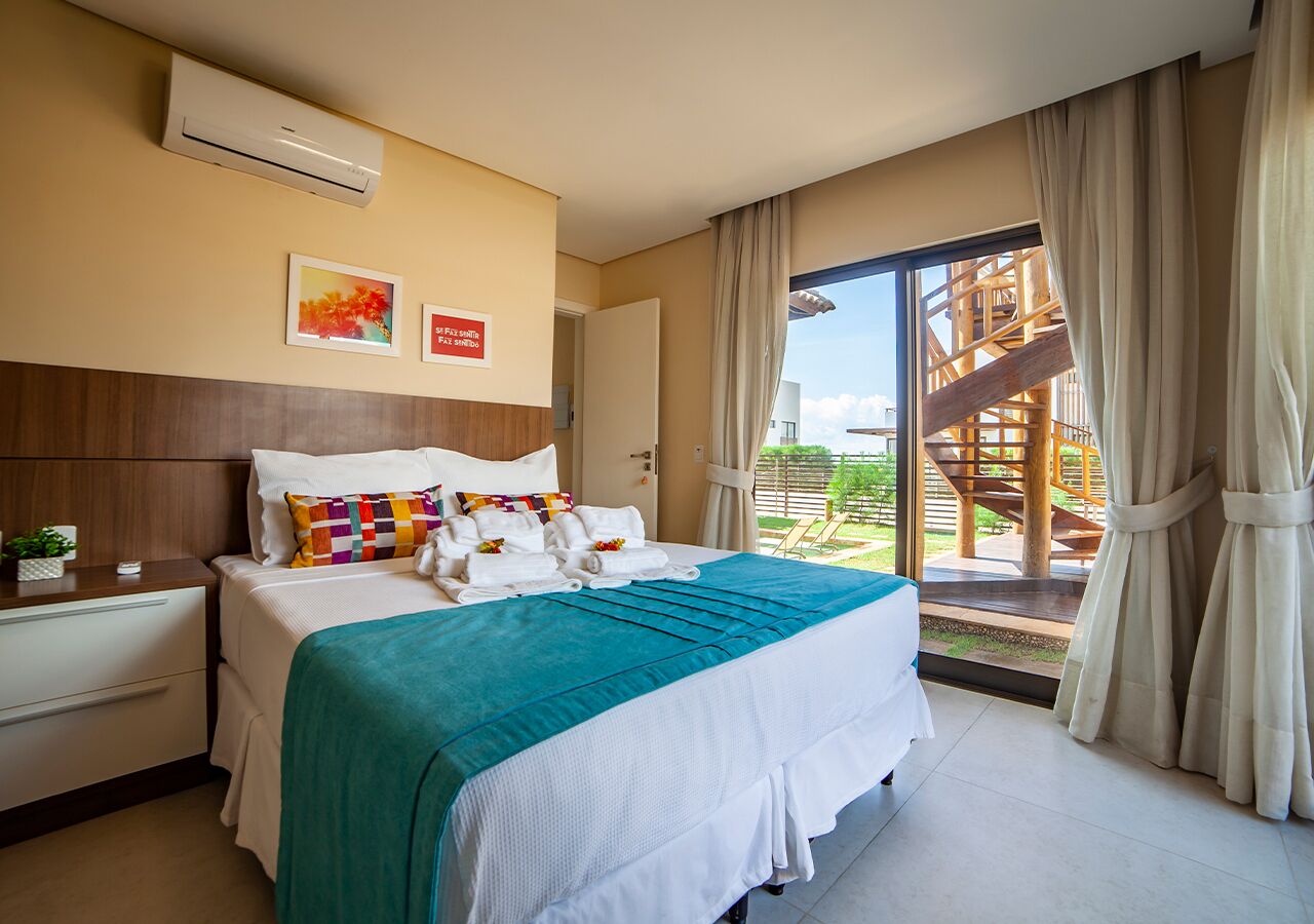 Une chambre d’hôtel avec un lit, une table de chevet, une fenêtre avec des rideaux et une vue sur une structure en bois à l’extérieur.