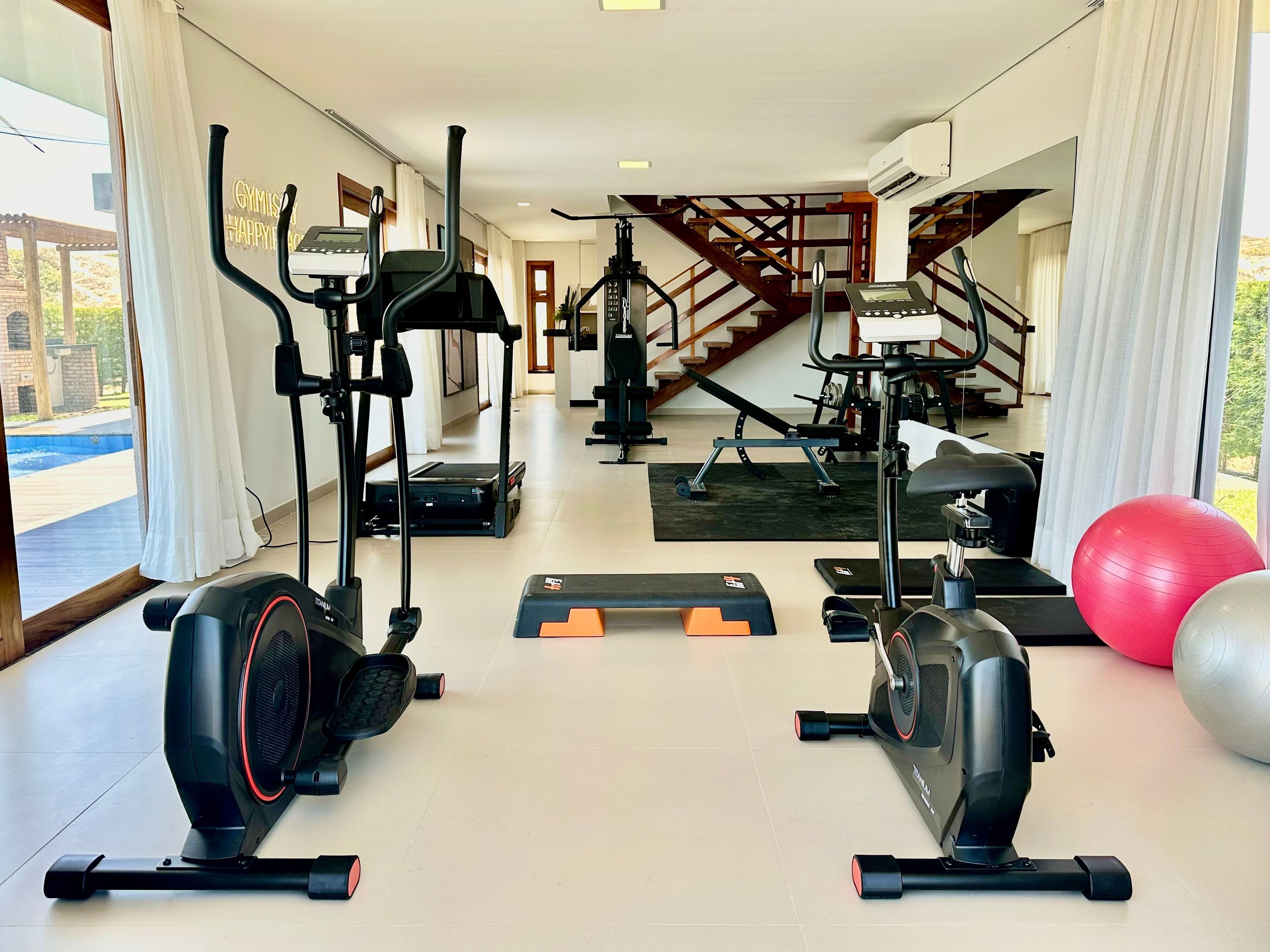 A gym with treadmills, elliptical machines, and exercise balls.