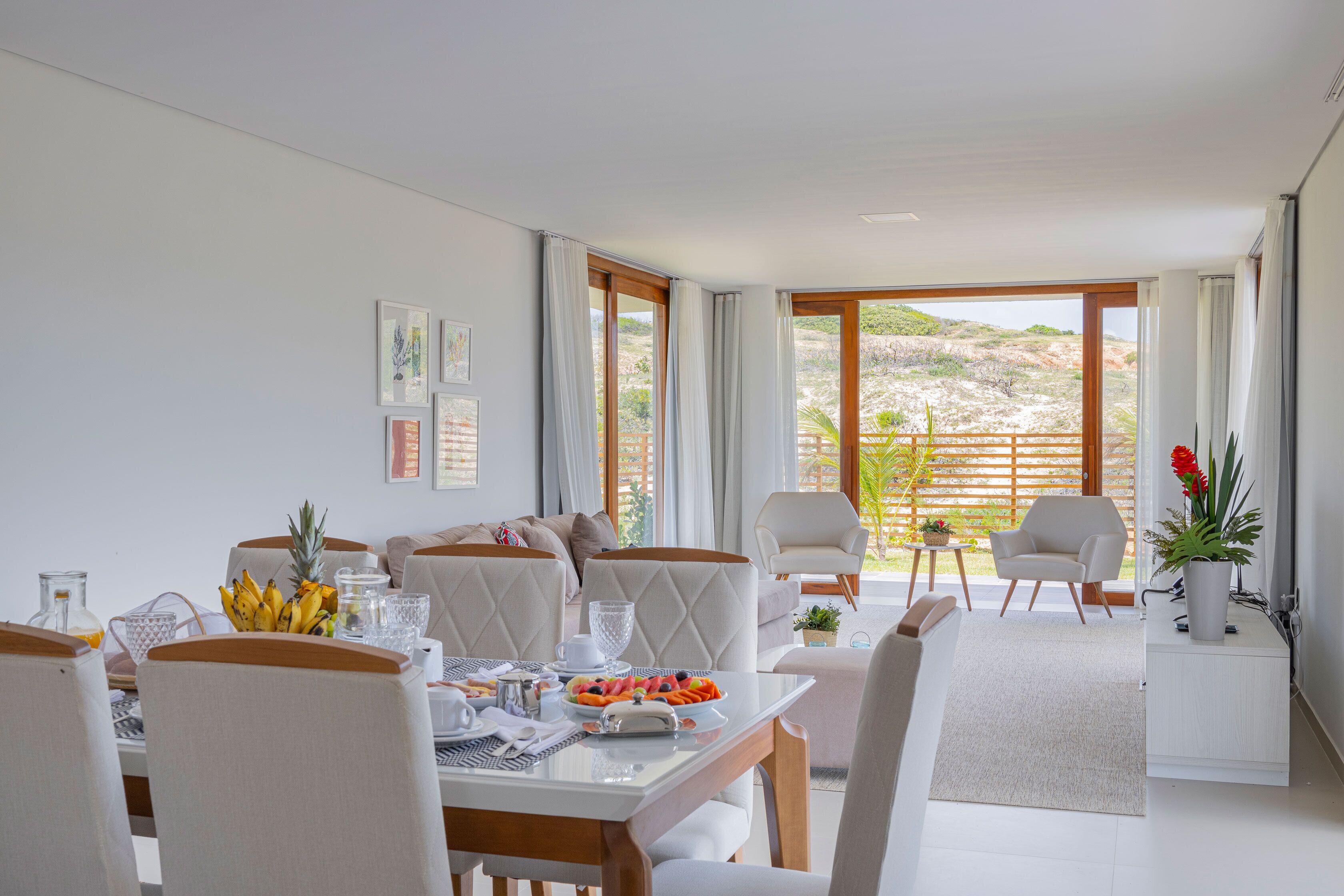 A modern dining area with a table set for two, a sofa, and a view of the outdoors.