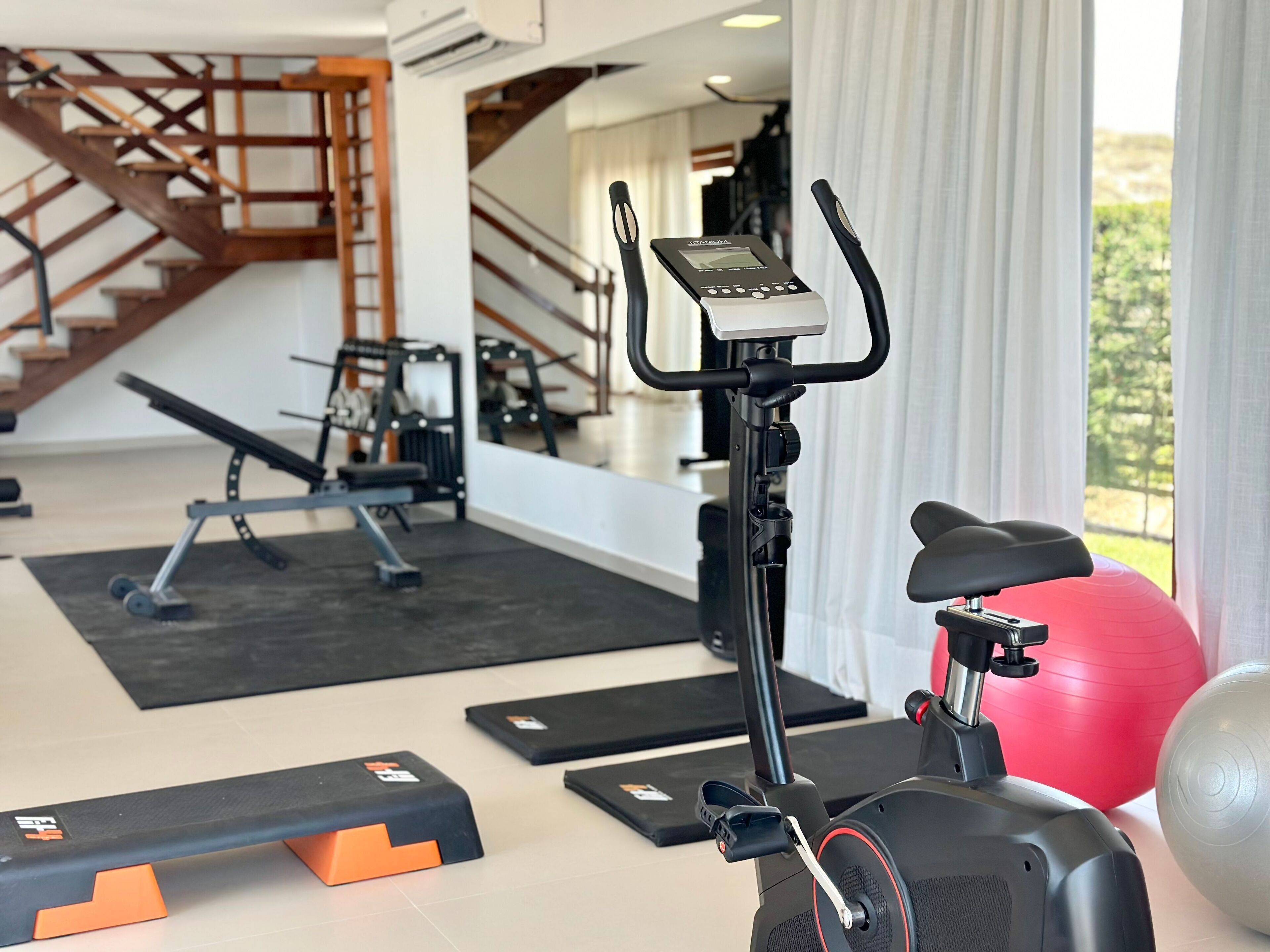 Ein Heimfitnessraum mit Crosstrainer, Gymbällen und Gewichtbänken.
