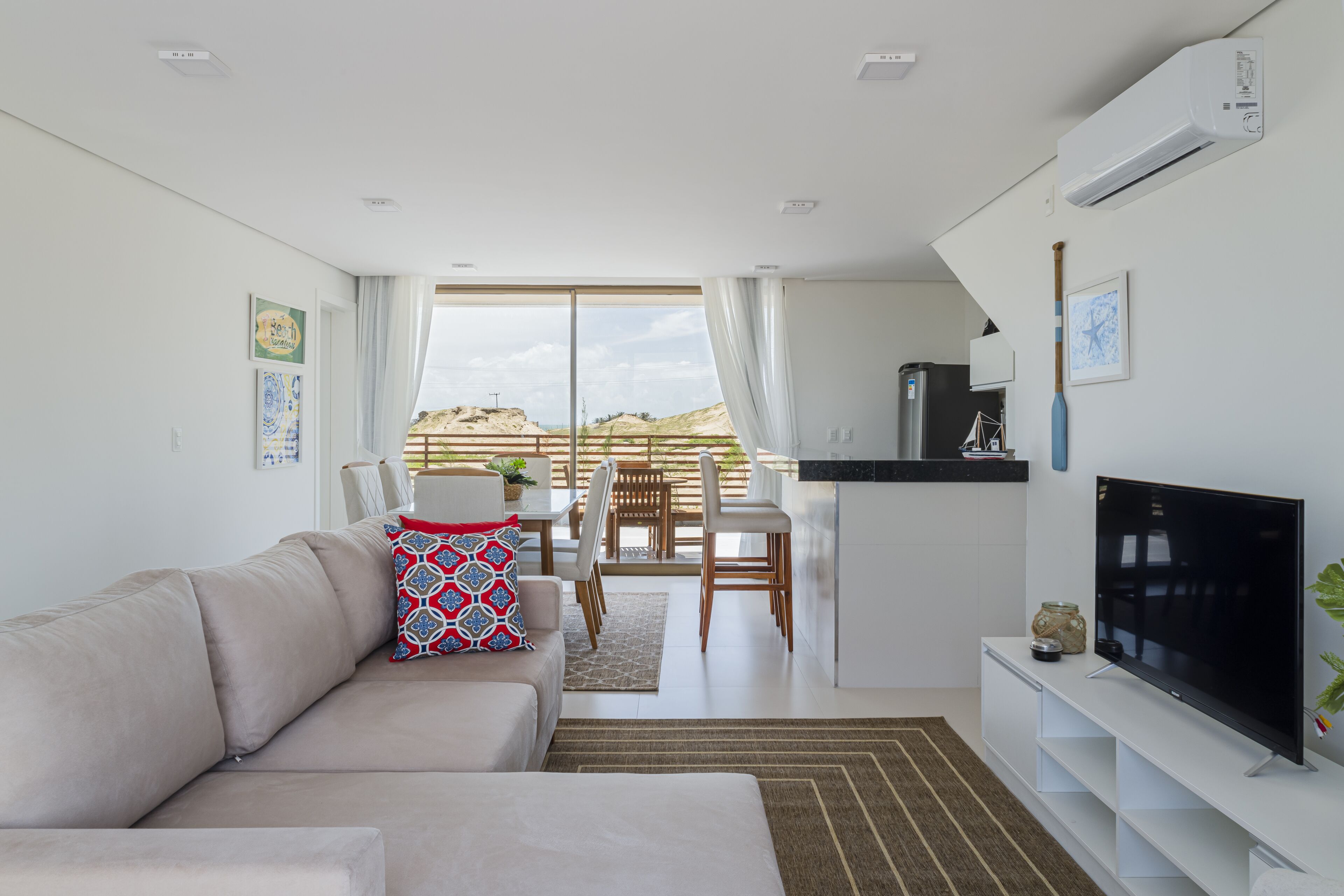 A modern living room with a sofa, TV, and a dining area with chairs and a table.