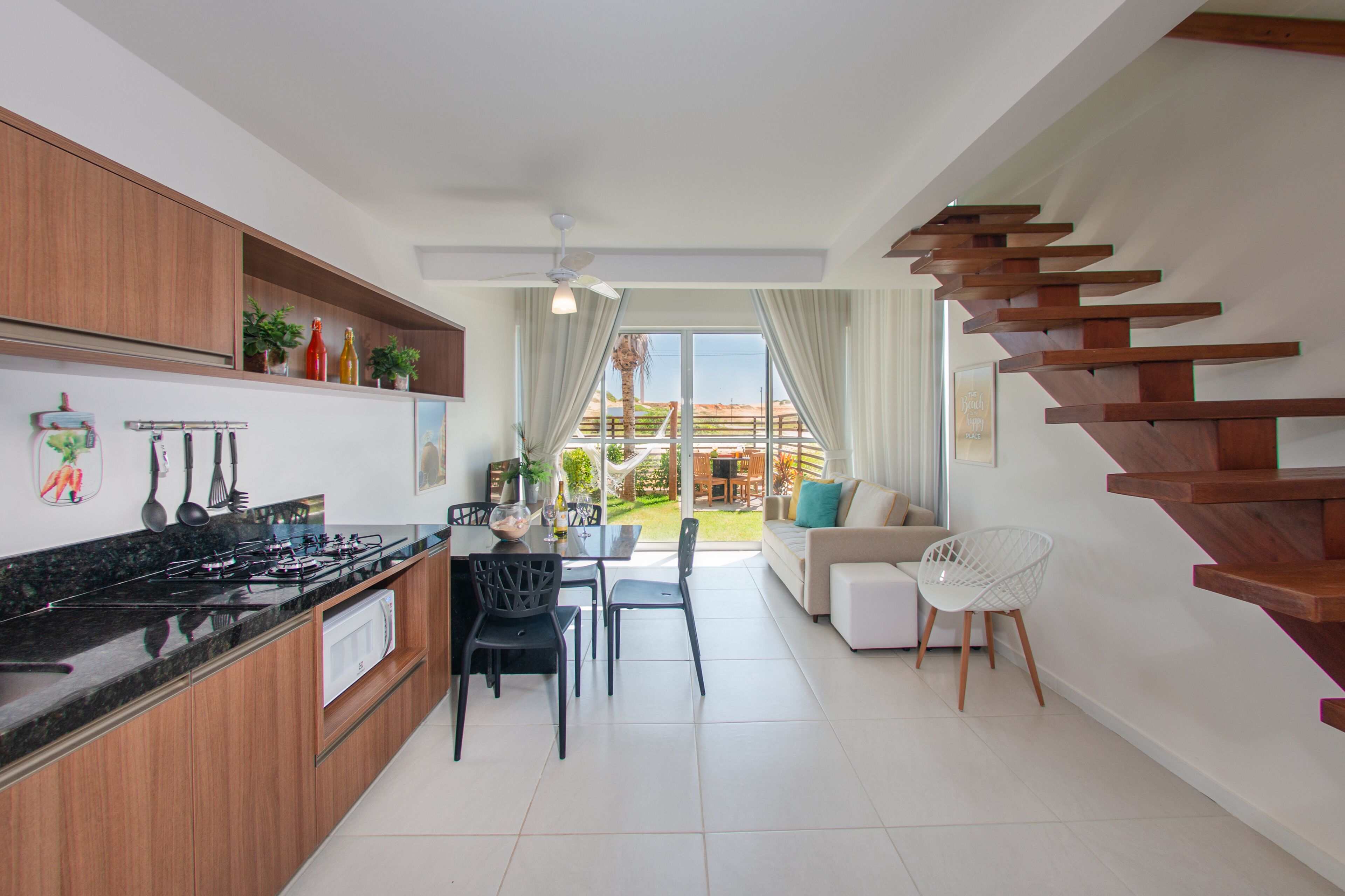 A modern kitchen with a dining area, a staircase, and a view of the outdoors.
