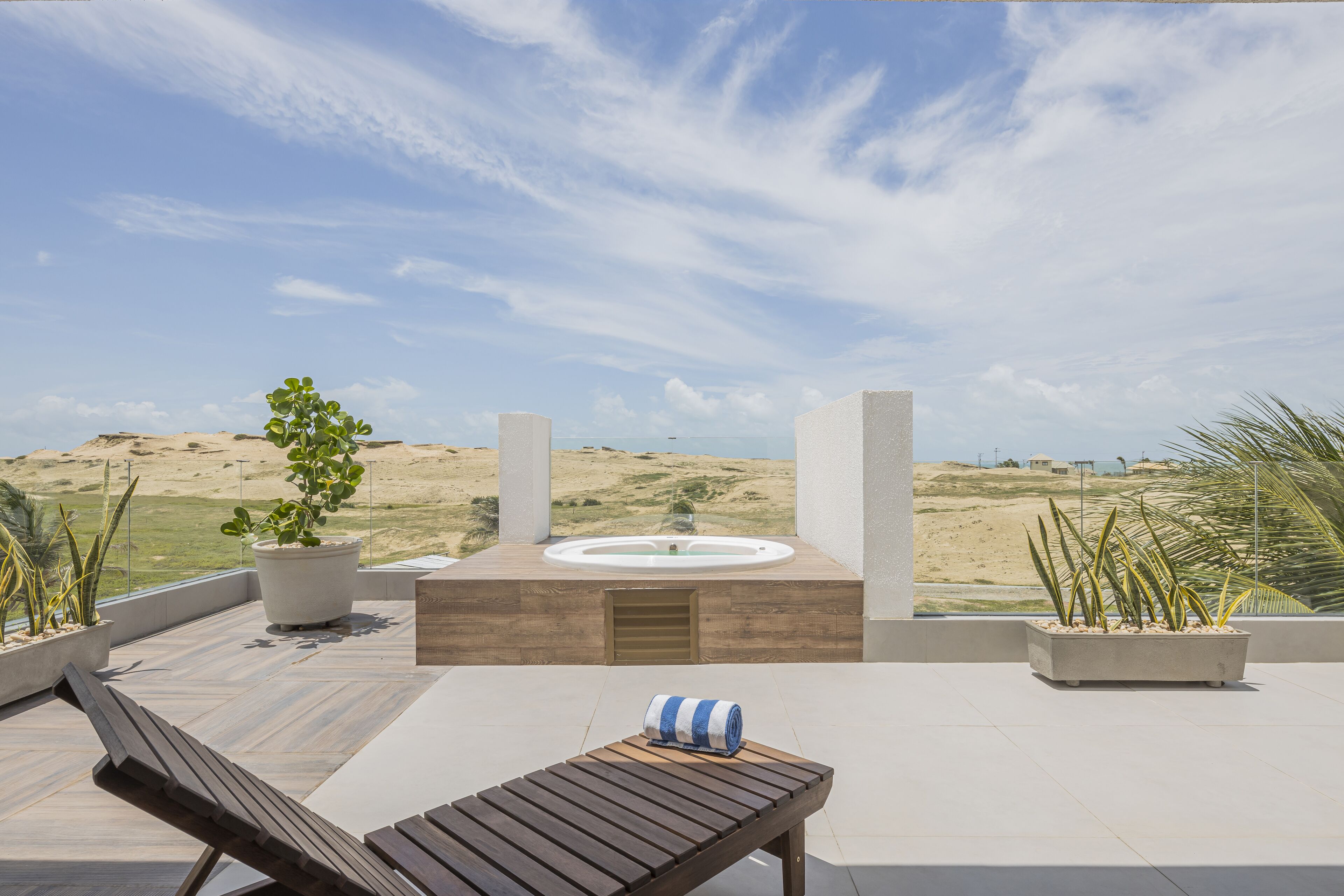 Una terraza en la azotea con una silla de mimbre, un jacuzzi y macetas con plantas.