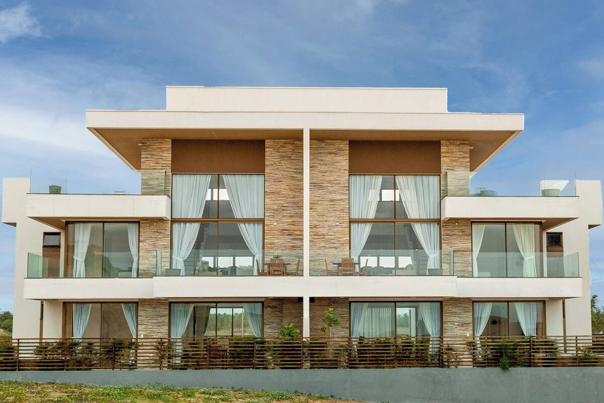 Un edificio moderno de varios pisos con amplios ventanales, techo plano y balcón.