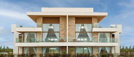 A modern multi-story building with large windows, a flat roof, and a balcony.
