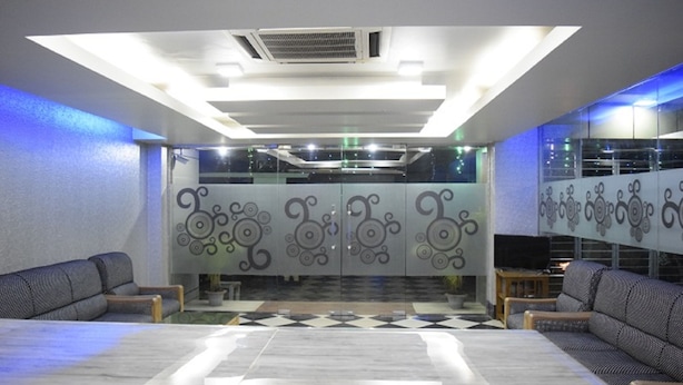 Uma sala de conferências moderna com piso de mármore, dois sofás, uma mesa grande e painéis decorativos na parede.