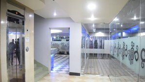 Um hall moderno com piso xadrez, paredes de vidro e uma escada.