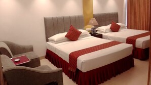 Quarto de hotel com duas camas, uma mesa e uma cadeira.