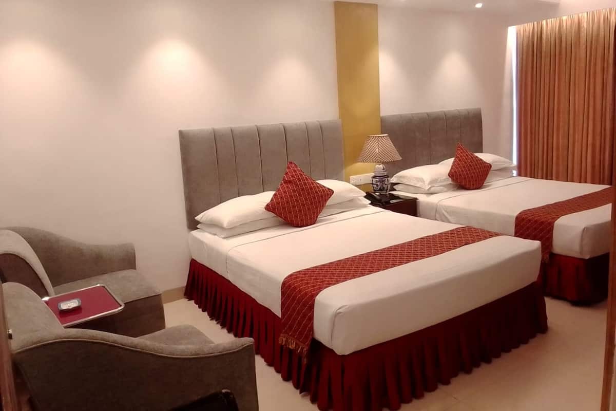 A hotel room with two beds, a desk, and a chair.