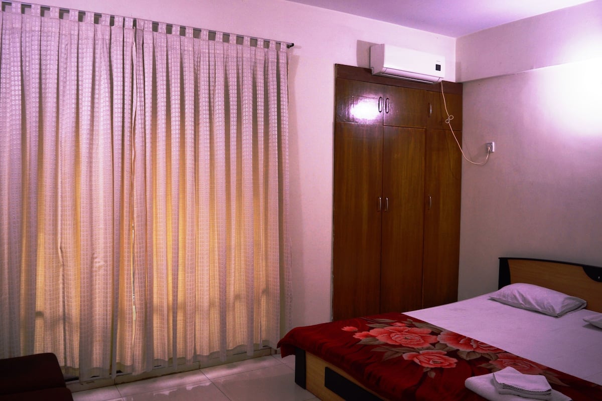 A bedroom with a bed, a wardrobe, and a curtain.