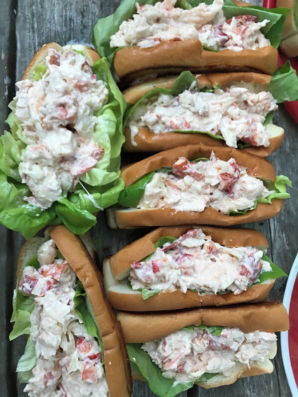 A tray of lobster rolls with lettuce and a red napkin.