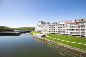 A large hotel with multiple floors, a swimming pool, and a green lawn.