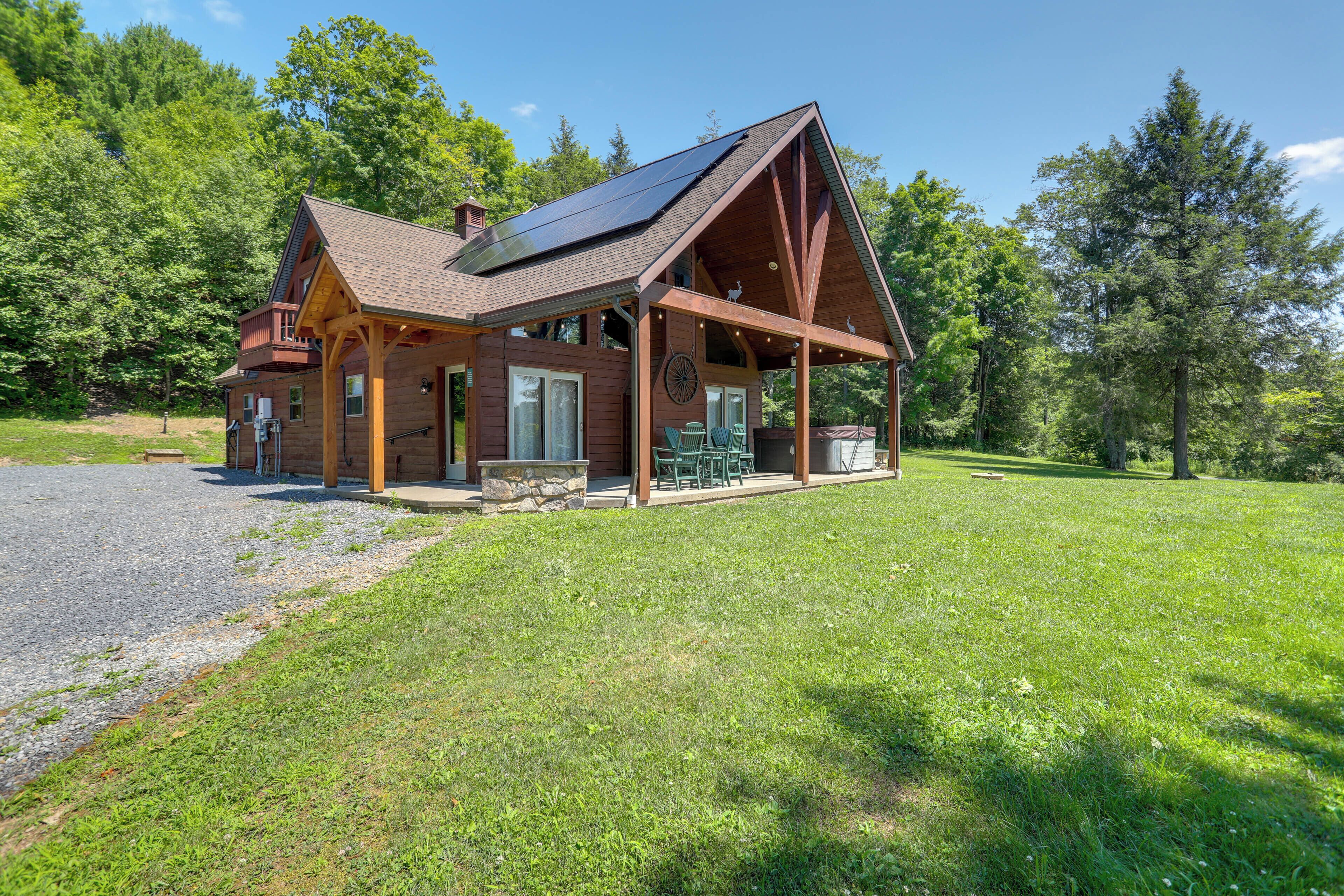 A wooden cabin with a sloped roof, a porch with outdoor seating, and a stone foundation.