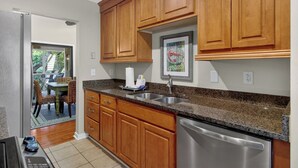 A kitchen with wooden cabinets, a stainless steel dishwasher, and a granite countertop.