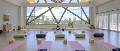 Amplia habitación con ventanas grandes, esterillas y bloques de yoga dispuestos para una clase.
