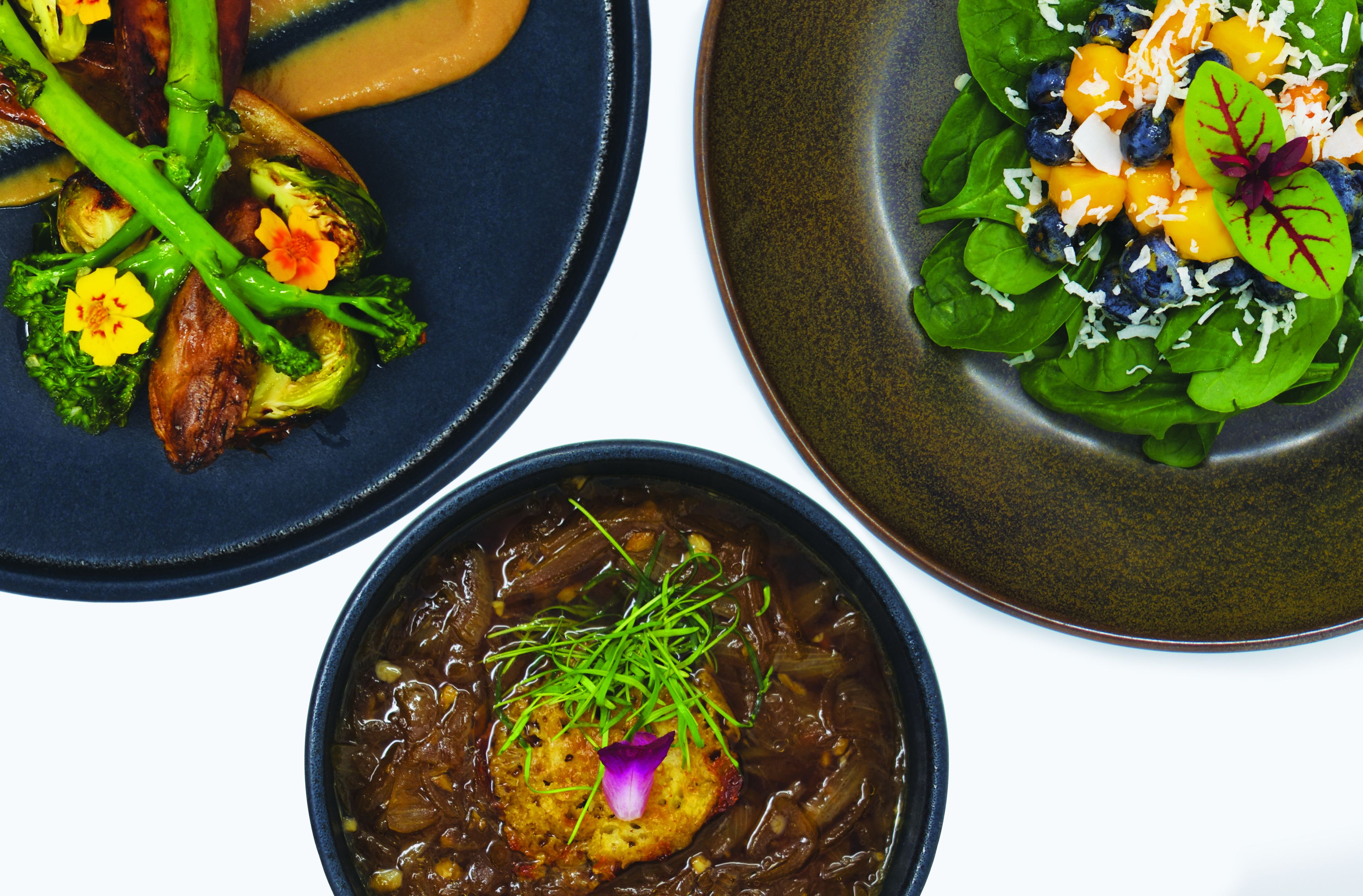 Tres platos con diversos vegetales y guarniciones.