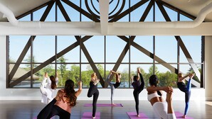 A spacious indoor area with large windows and a high ceiling, suitable for group activities like yoga.