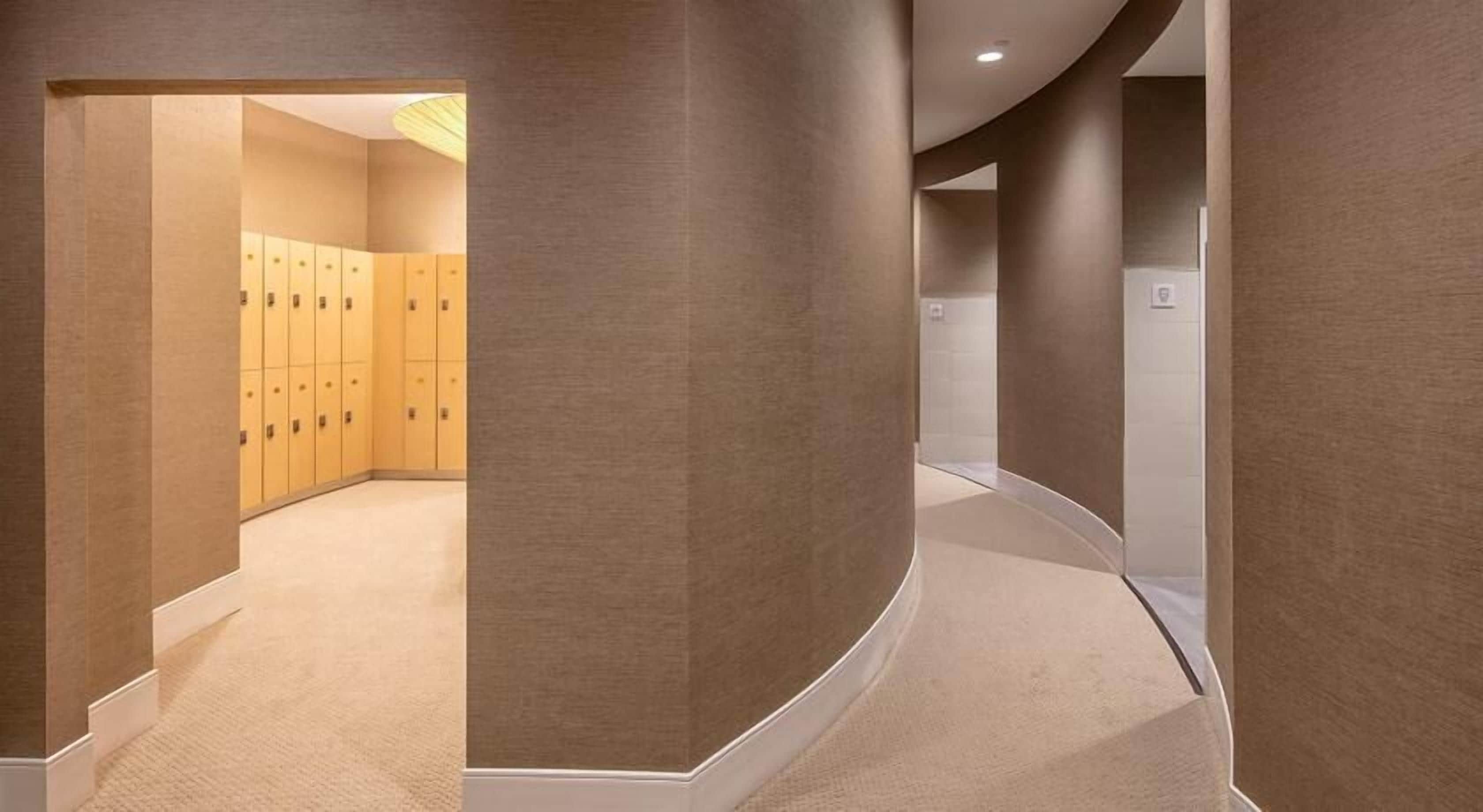 A hallway with lockers, curved walls, and a carpeted floor.