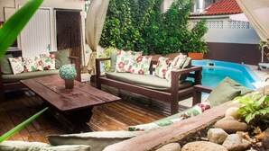 Una terraza de madera con un sofá, cojines y una mesita.