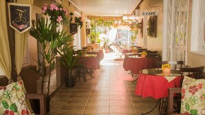 Un café con manteles rojos, plantas en macetas y un letrero que indica la zona de café.