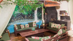 Un espacio exterior acogedor con mobiliario de madera y un mural de una cascada.