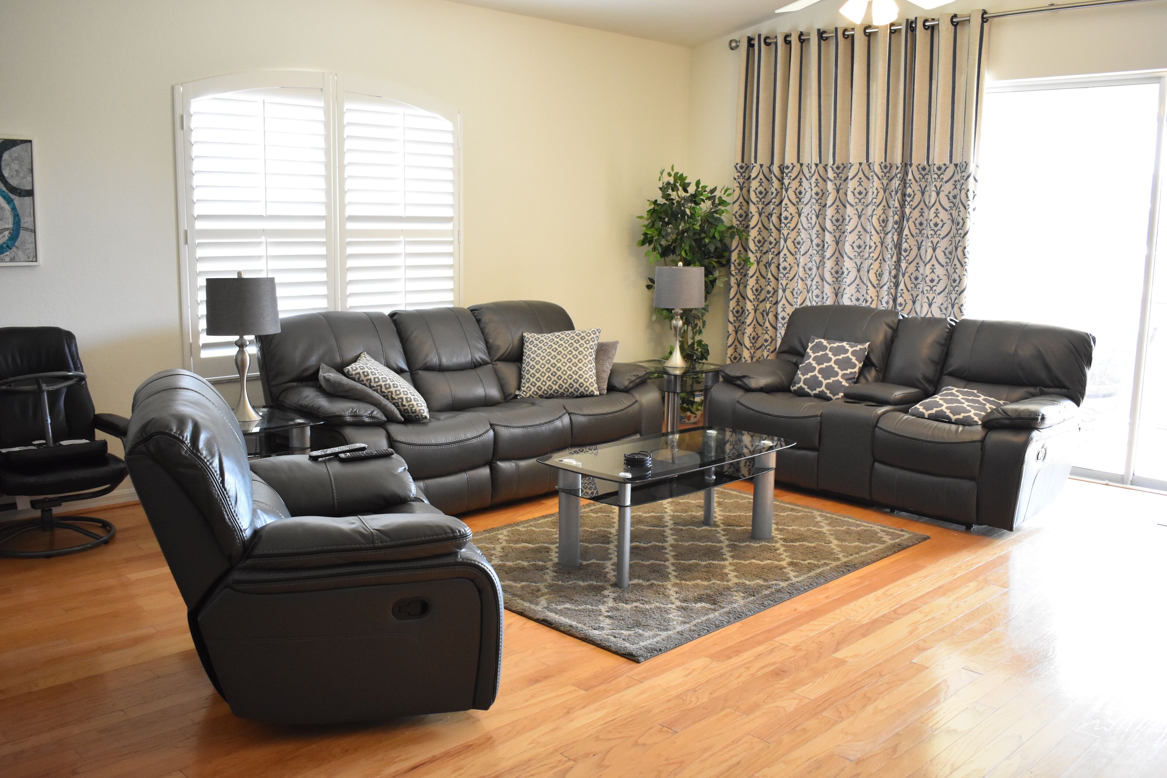 A modern living room with leather sofas, a glass coffee table, and a black armchair.