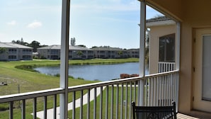 A view from a balcony overlooking a golf course with a water body, a pathway, and a building complex in the background. -  Beautiful Condo Close To Beaches (Bradenton)