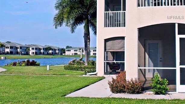 A two-story building with a balcony, a pool, and a view of other buildings across the water. -  Beautiful Condo Close To Beaches (Bradenton)