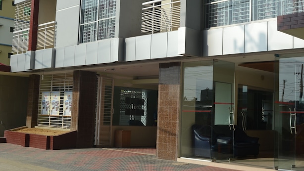 A modern building with a glass entrance, a seating area with a bench, and a staircase leading to an upper level. - Hotel Pink Shore (Cox's Bazar)