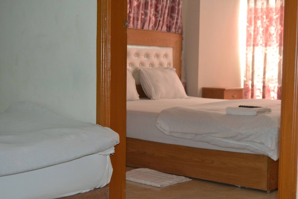 A bedroom with a single bed, a wooden headboard, and a nightstand.